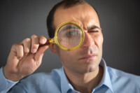 man looking through magnifying glass